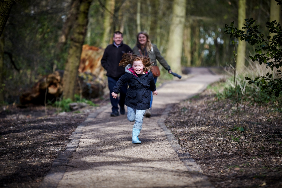   Girl running in woods as parents watch 