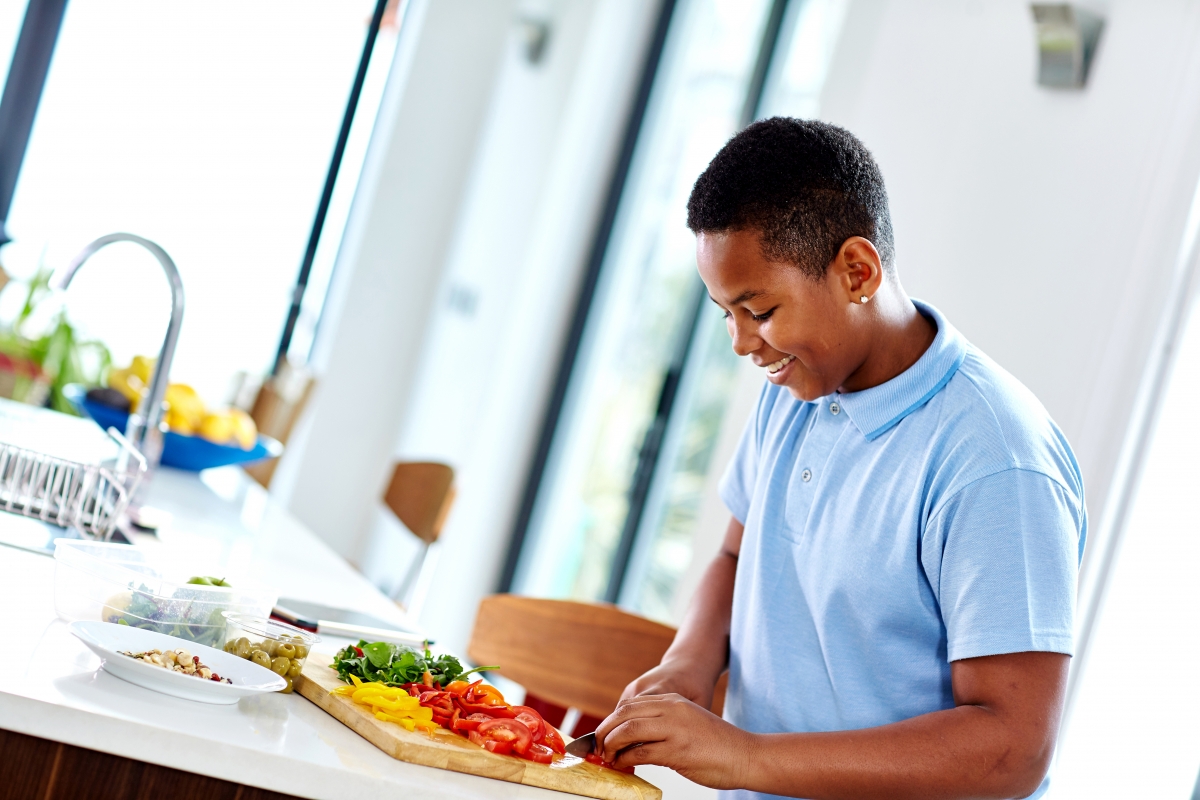 Boy chopping vegetables in Kitchen 