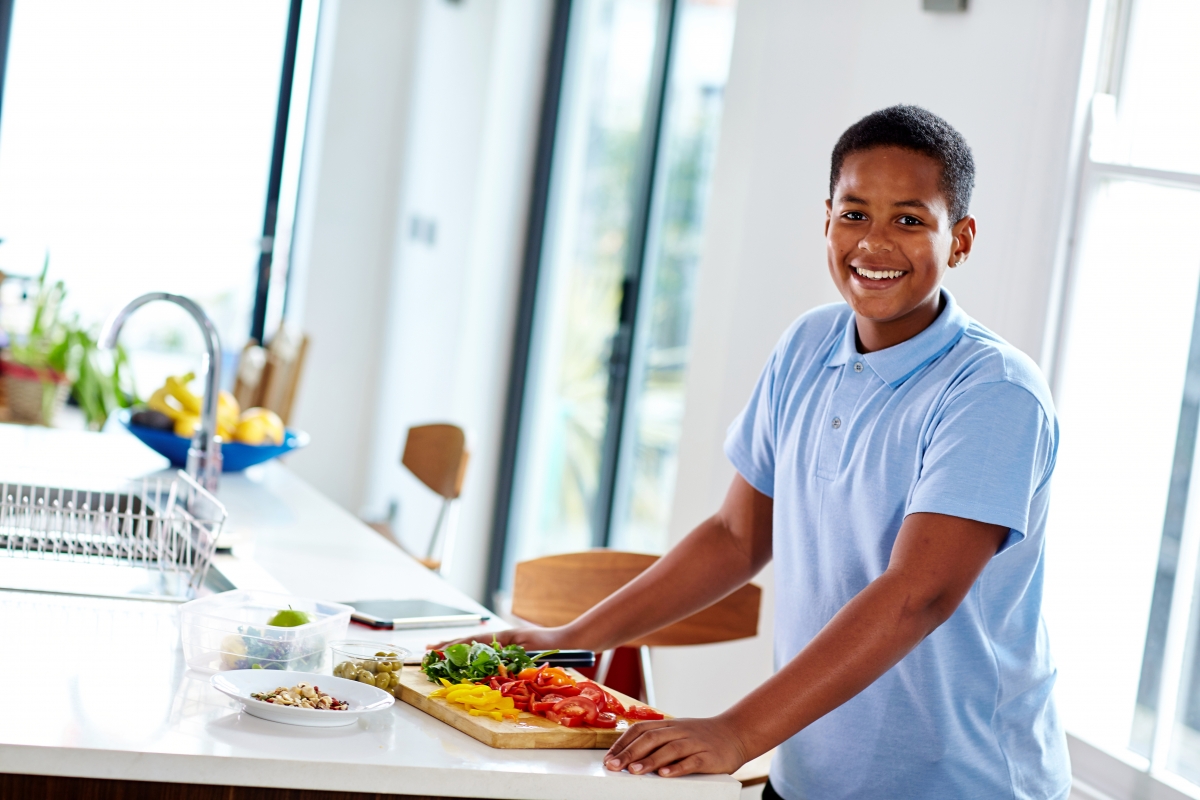 Boy smiling and chopping vegetables 